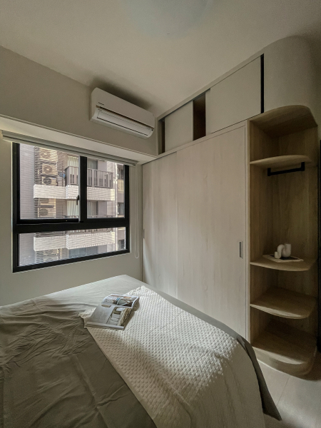 空間整體以白色及淺色木紋為主,入門採用開放式弧形設計,使得櫃體在空間感上不壓迫,搭配床頭跳色增添空間的溫柔感